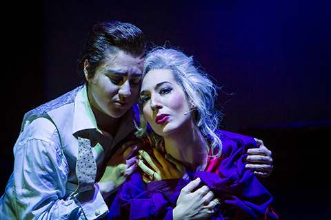 Two opera performers share a moment under the spot light during a performance