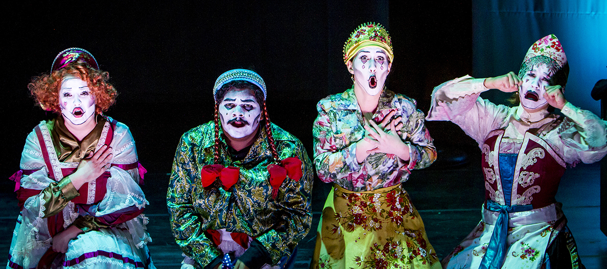 Actors with bright clothing and expressive makeup sign during an opera performance